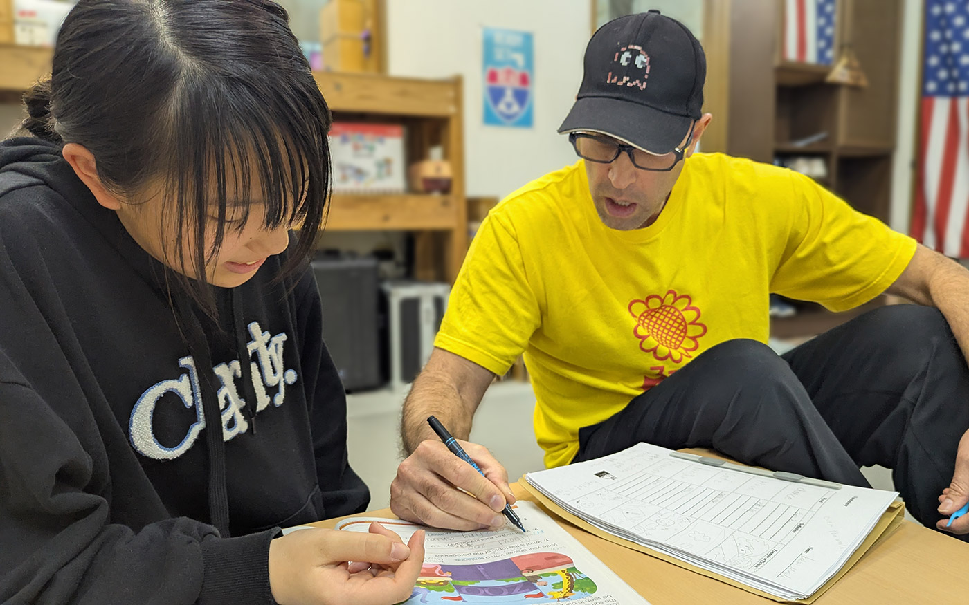 Advanced elementary student receiving focused English grammar instruction while completing worksheet with teacher support