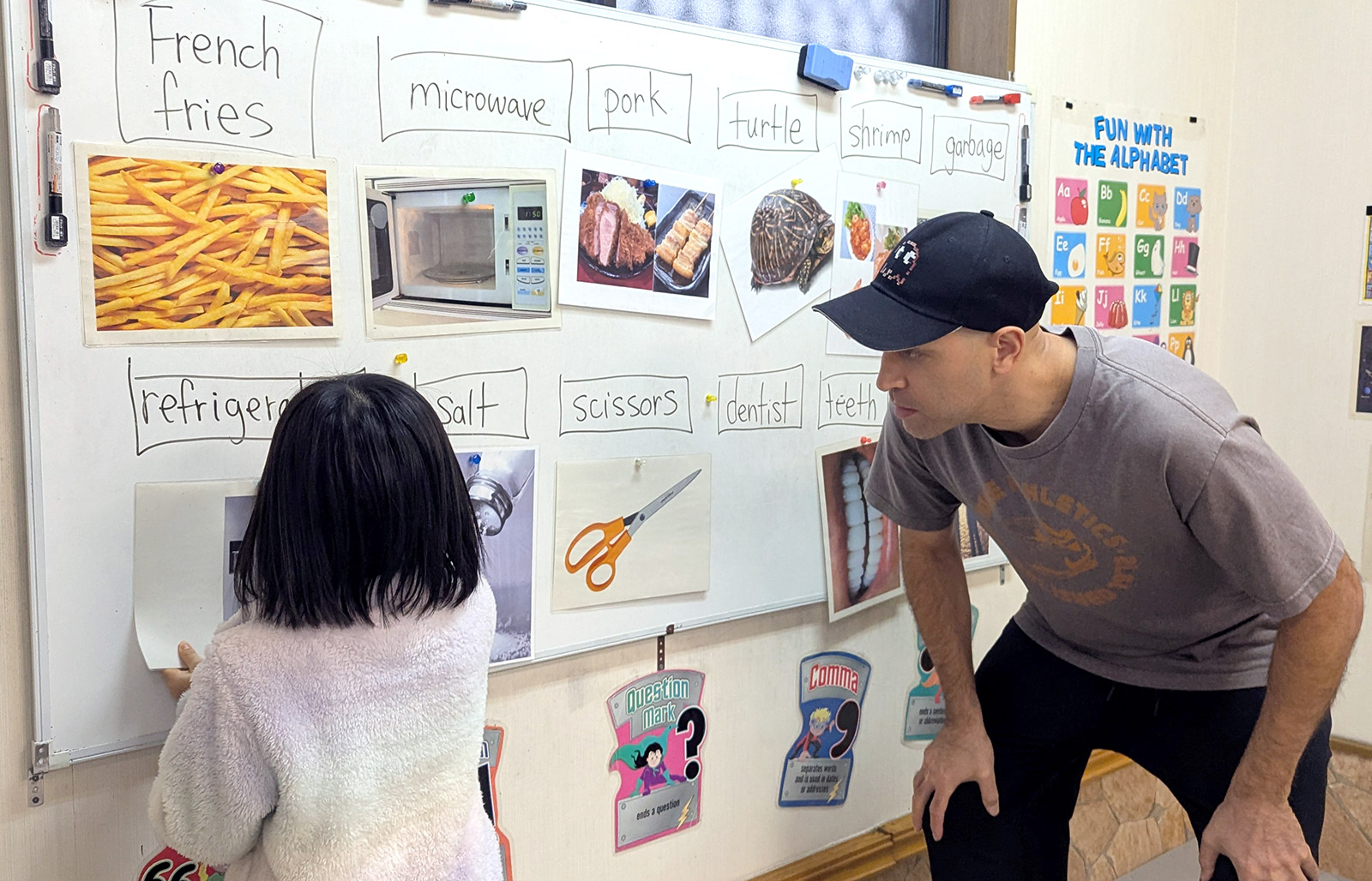 Elementary school student learning English vocabulary at the whiteboard with teacher guidance